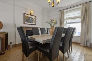 a dining room with a table and black chairs at Marina Cottage - Waterside Views Kingswear in Kingswear