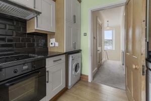 a kitchen with a stove and a washer and dryer at Marina Cottage - Waterside Views Kingswear in Kingswear