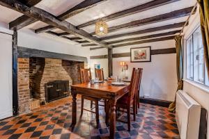een eetkamer met een tafel en een open haard bij Boldshaves Cottage in Woodchurch