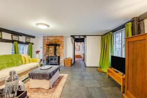 een woonkamer met een bank en een tv bij Boldshaves Cottage in Woodchurch