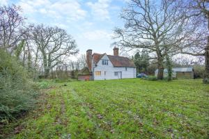 een oud huis in een veld met een grasveld bij Boldshaves Cottage in Woodchurch