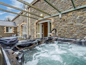 a hot tub in front of a stone house at 3 Bed in Builth Wells 52463 in Alltmawr
