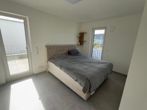 un letto in una camera bianca con due finestre di Villa am Rhein in Monheim a Monheim