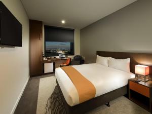 a hotel room with a bed and a flat screen tv at ibis Brisbane Airport in Brisbane