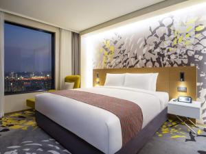une chambre avec un grand lit et une grande fenêtre dans l'établissement Novotel Suites Ambassador Seoul Yongsan, à Séoul