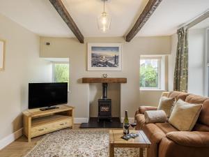 a living room with a couch and a tv and a fireplace at Lane Ends Cottage in Disley