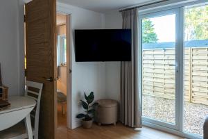 a living room with a sliding glass door with a television at The Perk Inn Garden Lodge in Broadstone