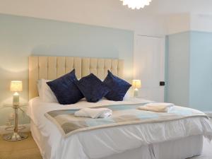 a bedroom with a large bed with blue pillows at Burnbrae Cottage in Bridgend of Lintrathen +9 photos