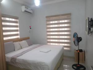 a white bedroom with a bed and a fan at 2 Bedroom apartment in Ikeja with free wifi in Ijaiye