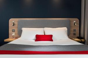 a bed with two white pillows and a red pillow at Holiday Inn Express London-Hammersmith by IHG in London