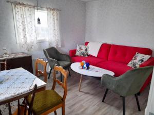 Una sala de estar con un sofá rojo y sillas. en Cozy country cottage in scenic location near Monsteras, en Alebo 12 fotos más
