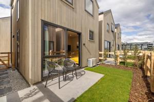 two chairs sitting on a patio in front of a building at Villa XV Stylish and Contemporary Escape in Queenstown Airport