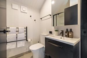 a white bathroom with a toilet and a sink at Villa XV Stylish and Contemporary Escape in Queenstown Airport +11 photos