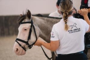 ウルラにあるMANEJ URLAの茶色と白の馬を抱えた女性