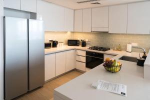 une cuisine avec des armoires blanches et un réfrigérateur dans l'établissement Yas Island Resort Beach Access Luxury in Mayan 1 BEDROOM, à Yas Island