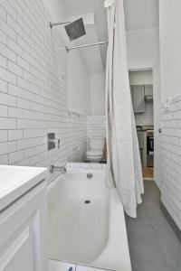 a white bathroom with a toilet and a sink at 2 BD Tranquil Unit close to Central Park in New York +15 photos