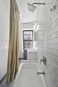 a white bathroom with a tub and a sink at 2 BD Tranquil Unit close to Central Park in New York