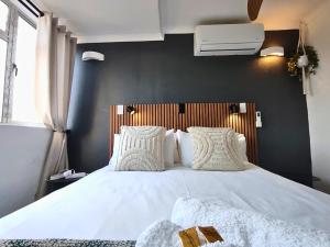 a bedroom with a white bed with a black wall at Cosy Beach Cottage 52 Chaka's Rock Chalets Resort in Ballito +15 photos