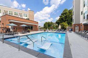 een groot zwembad met stoelen en een gebouw bij Unique Living 5 Min From Downtown in Wilders Grove