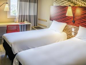 a hotel room with two beds and a desk at ibis Copiapo in Copiapó