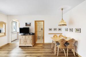 ein Esszimmer mit Tisch und Stühlen und einem Fernseher in der Unterkunft Fewo Brünnstein - Nr 44 Pool, Sauna in Oberaudorf