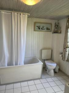 La salle de bains blanche est pourvue d'une baignoire et de toilettes. dans l'établissement Alte Liebe, à Dörphof 11 autres photos