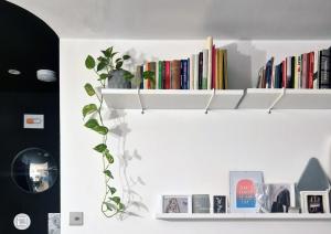 a white shelf with books and a plant on it at Renovated 1B Studio Apartment w Balcony in Central Brixton in London