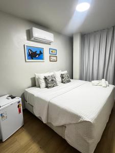 a bedroom with a large bed with white sheets at Suítes Viver Arraial do Cabo in Arraial do Cabo
