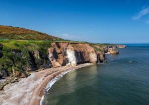 a beach with a waterfall on the side of a cliff at 3-BR Beachside Escape -Perfect for Families & Groups -Spacious & Cozy in Hawthorn
