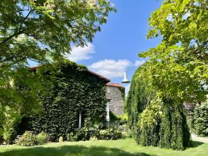 a building covered in ivy next to a house at Les Hirondelles du Marais in Ennezat