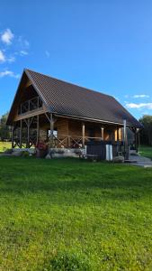 a large log cabin with a grass field in front of it at Ramaus poilsio sodyba in Petruniškis