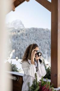 een vrouw die een foto neemt van een berg met een camera bij Alpstay - Hotel Acadia - Adults Mountain Home in Selva di Val Gardena
