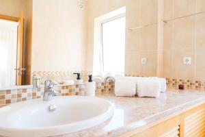 ein Badezimmer mit einem weißen Waschbecken und einem Spiegel in der Unterkunft T3 Praia del Rey, piscina e vista mar, Óbidos, A7 in Óbidos + 25 Fotos