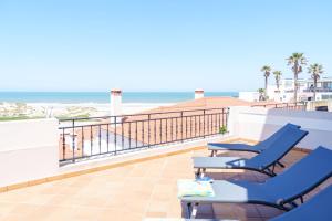 einen Balkon mit blauen Stühlen und Strand in der Unterkunft T3 Praia del Rey, piscina e vista mar, Óbidos, A7 in Óbidos