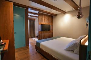 a bedroom with a bed and a flat screen tv at Palorto Hotel in Gjirokastër