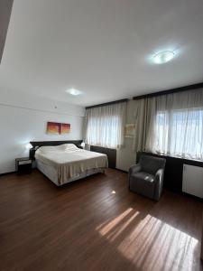 a bedroom with a bed and a chair in it at Hotel Mercu Paraíso Benefência c garagem e cozinha 1606 in Sao Paulo