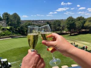 twee mensen met champagneglazen voor een golfbaan bij Private Solarium - Golf and Pool View - Las Ramblas 830 in Orihuela-Costa