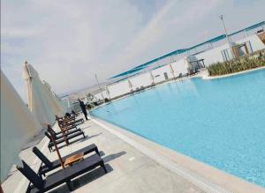 a large swimming pool with chairs and an umbrella at A unos pasos de la Arena in Puerto Viejo