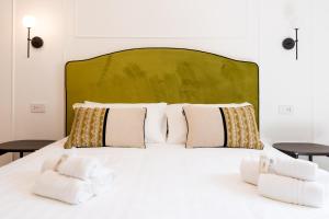 a white bed with white pillows and a green headboard at Marmori Suites Cagliari in Cagliari +6 photos