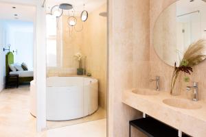 a bathroom with a tub and two sinks and a mirror at Marmori Suites Cagliari in Cagliari