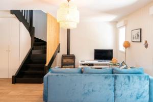 a living room with a blue couch and a staircase at Maison de vacances Oceanides in Capbreton