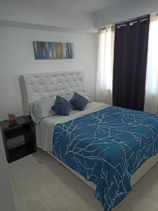 a bedroom with a bed with a blue comforter at Bello Apartamento en Playa Lido, lechería in El Morro de Barcelona +13 photos