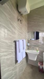 a bathroom with a sink and towels on a wall at Beeba's Suite in Kwabenya