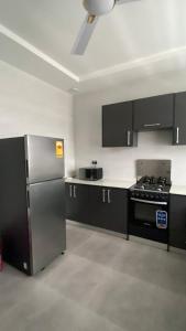 a kitchen with black cabinets and a stainless steel refrigerator at Beeba's Suite in Kwabenya