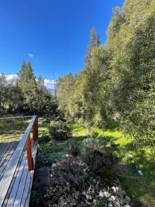 Una terraza de madera en un jardín con árboles. en Ventanas al Nahuel Huapi, en San Carlos de Bariloche