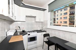 a kitchen with white cabinets and a sink and a window at Amber room in Sopot