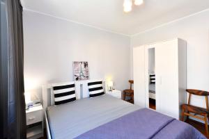 a white bedroom with a bed and a chair at Amber room in Sopot