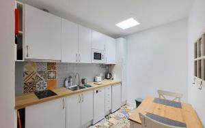 a kitchen with white cabinets and a wooden table at Casa Miradouro das Beatas in Elvas