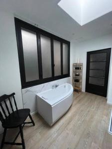 a bathroom with a bath tub and a chair in it at Appartement au centre de Boulogne-sur-Mer in Boulogne-sur-Mer +1 photo