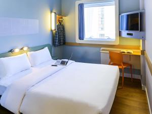 サンベルナルド・ド・カンポにあるIbis Budget São Bernardo do Campoの白いベッドと机と窓のある寝室